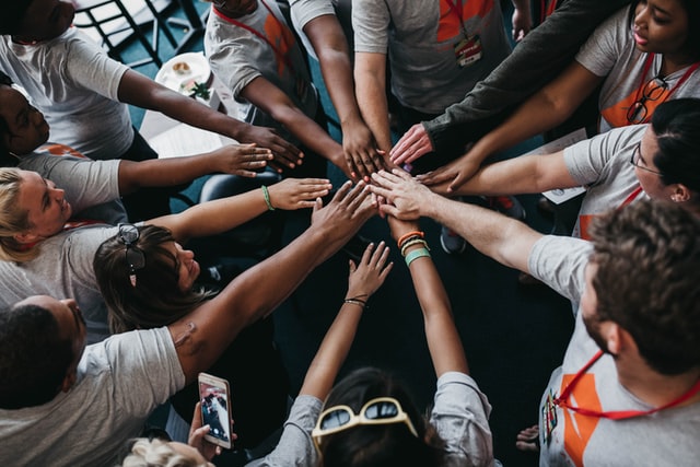 Image of people in a circle with their hands in the middle.