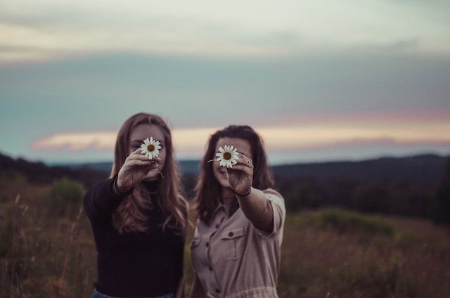 photo of two people holding daisies