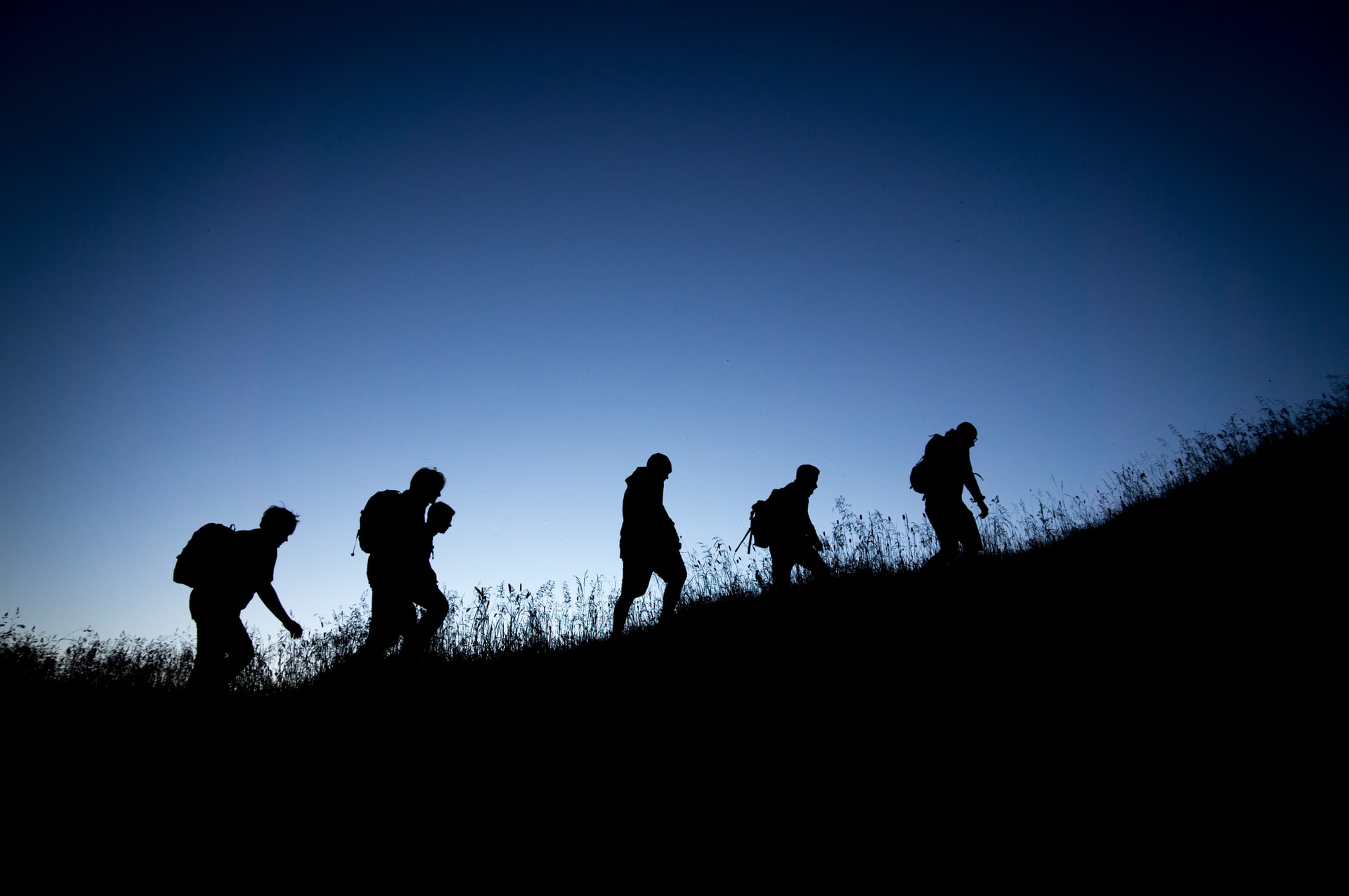 Silouette of people climbing a hill
